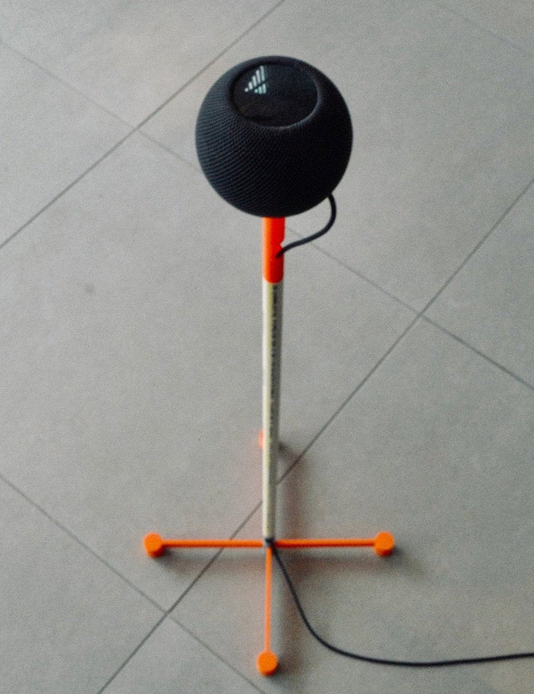 3D-printed DIY HomePod floor stand with an orange printed base and PVC post, holding a black Apple HomePod