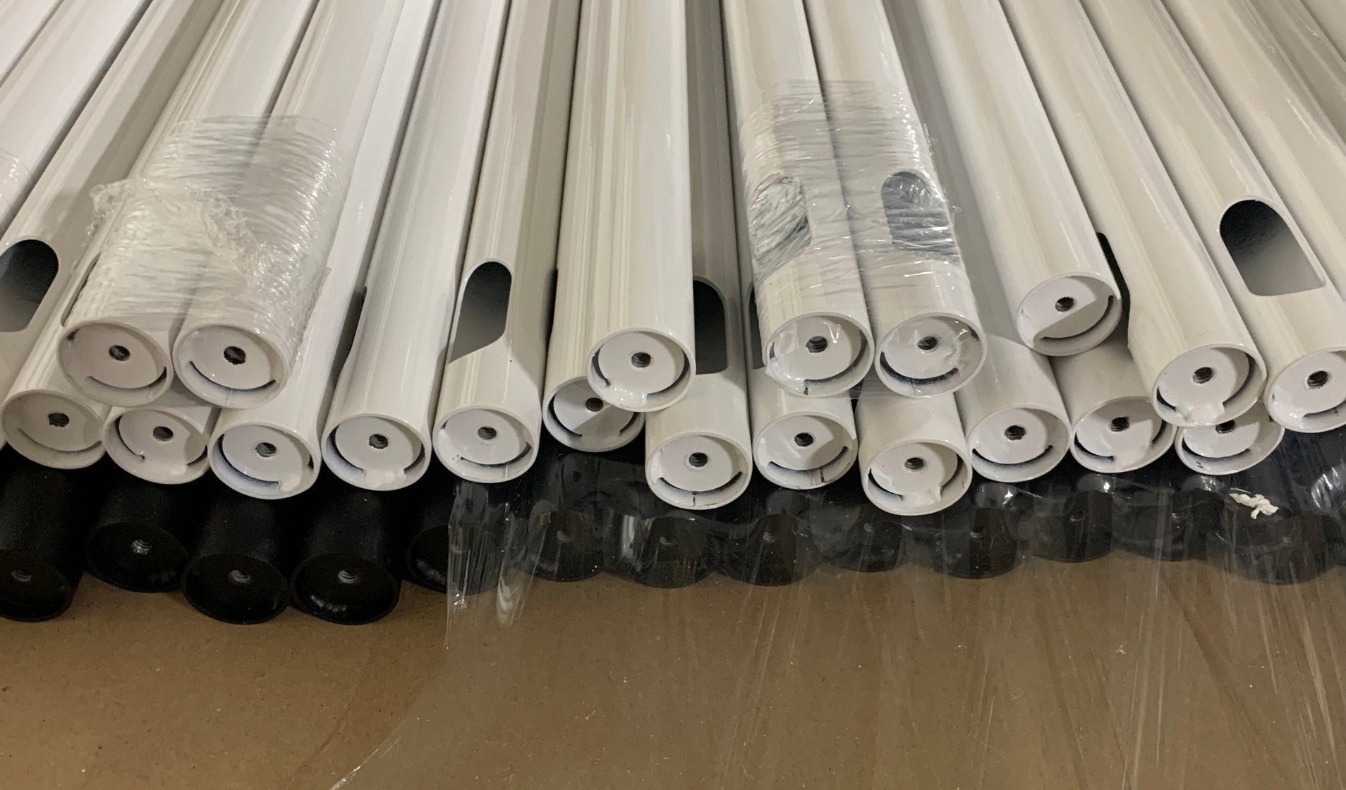 Bundles of white and black NoBox stand posts wrapped and stacked, ready to ship