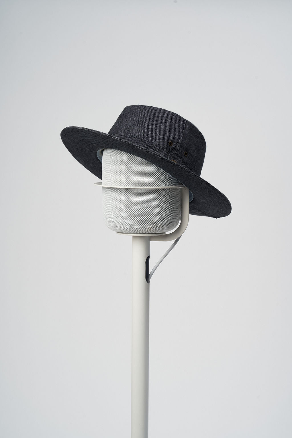 White NoBox HomePod floor stand holding a white Apple HomePod wearing a denim hat